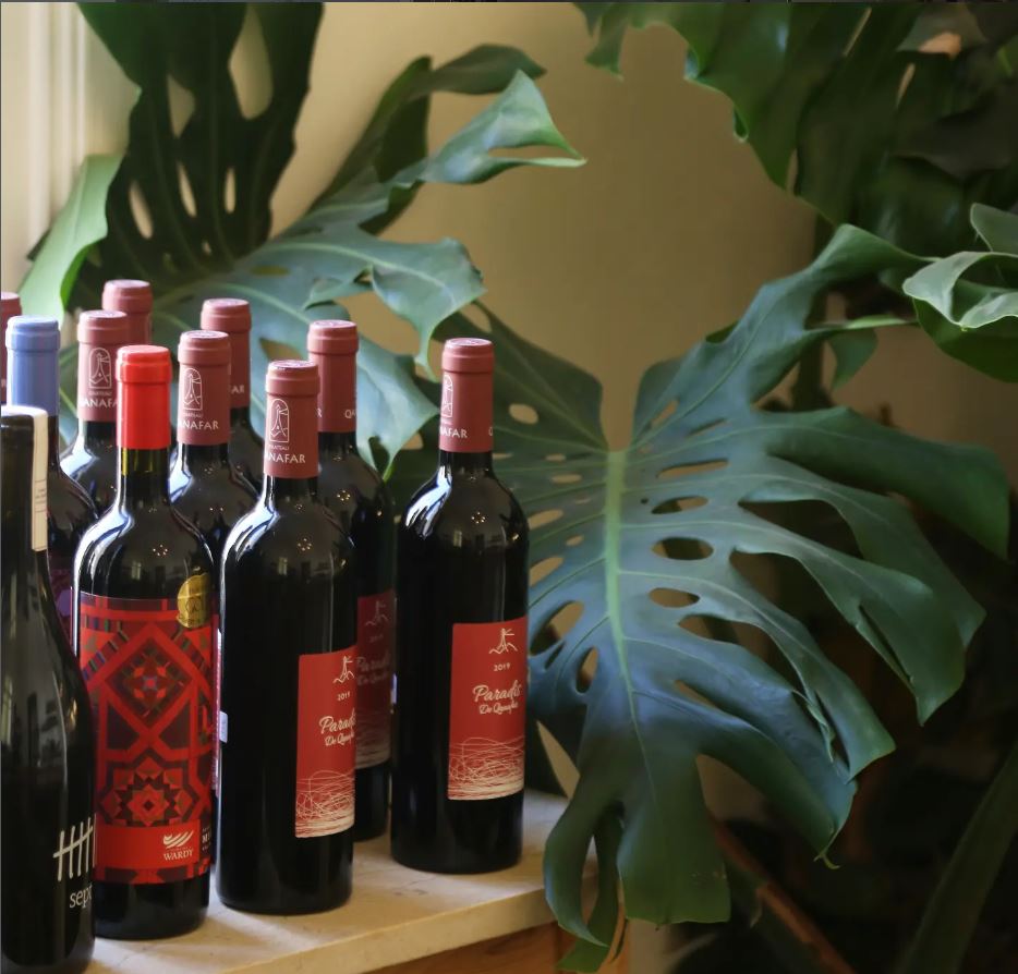Wine bottles on a shelf among plants at BEYt