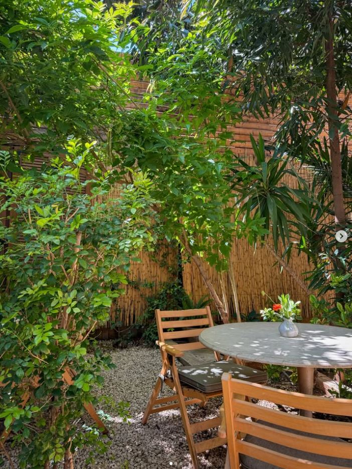 Wrought-iron balcony table with a drink, surrounded by greenery at BEYt